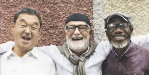 Three older men, Asian, white, and black, are smiling.